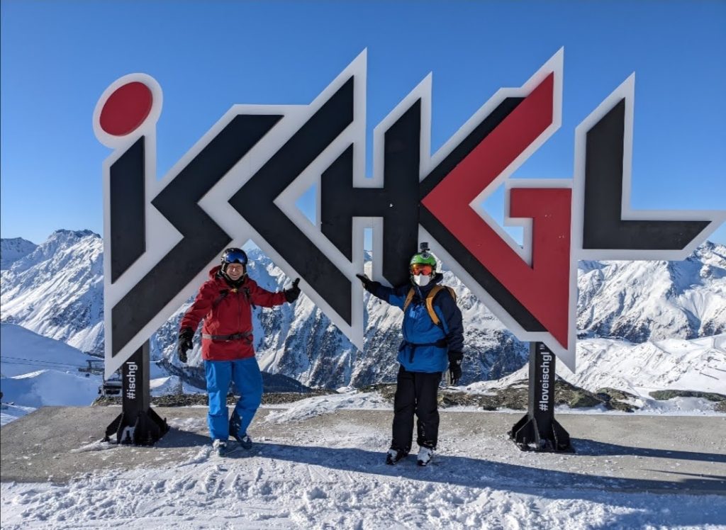 two skiers posing in front of the ischgl sign